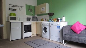 A compact kitchen with a microwave, oven, and washing machine. - No 8 Apartments (Bristol)