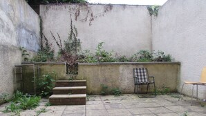 A concrete patio with steps leading to a wall, a metal chair, and a checkered chair. - No 8 Apartments (Bristol)