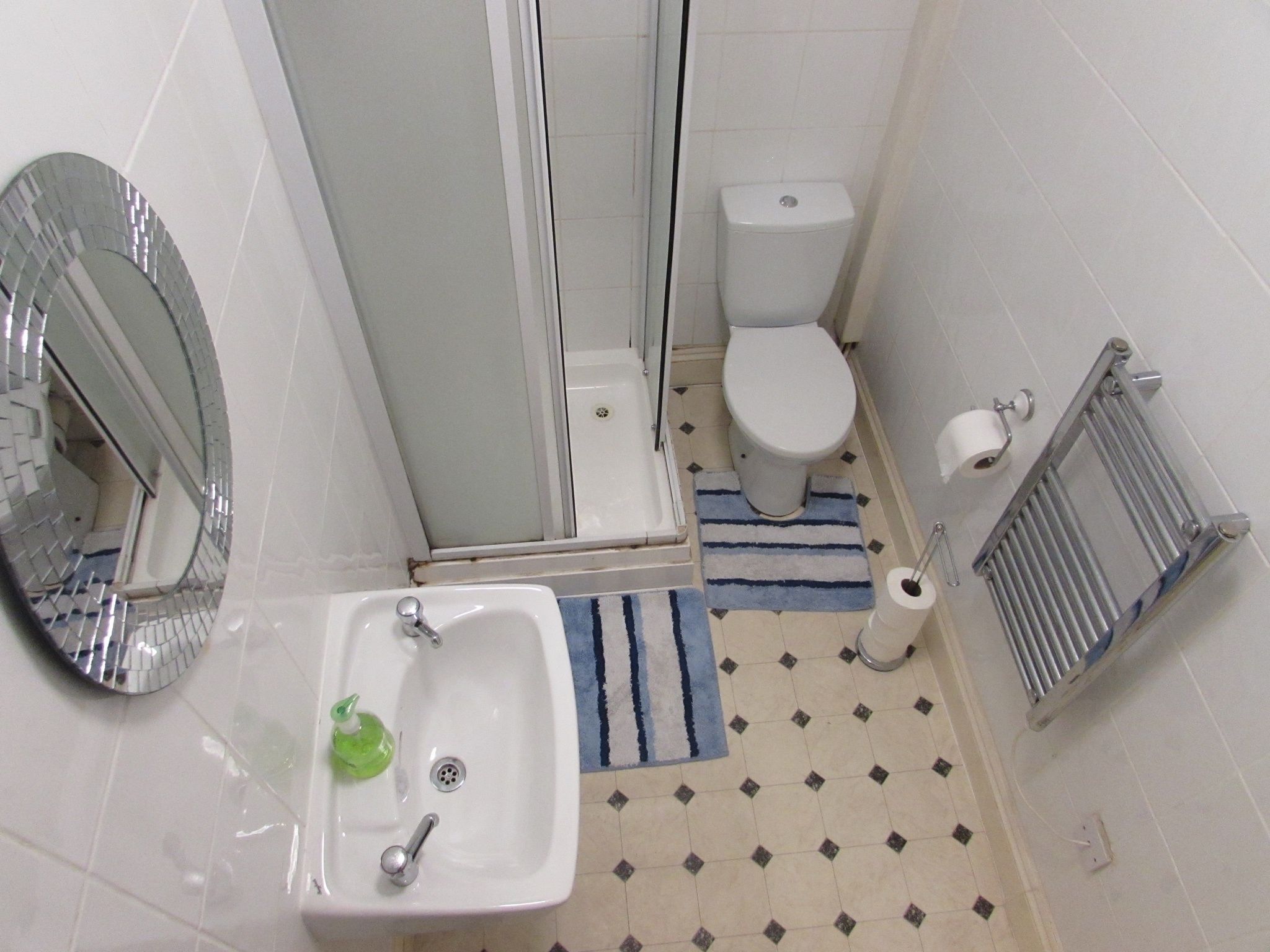 A small bathroom with a sink, toilet, and shower.