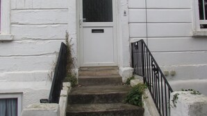 A white building with a front door, a small window above the door, and a staircase leading up to the door. - No 8 Apartments (Bristol)