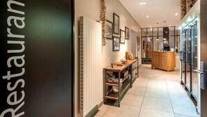 A modern restaurant interior with a long counter, wooden shelves, and framed pictures on the wall. - Hôtel Burnichon (Vindry-sur-Turdine)