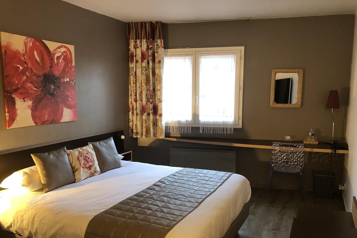Una habitación de hotel con una cama grande, un escritorio, una silla, una ventana con cortinas y un espejo en la pared.