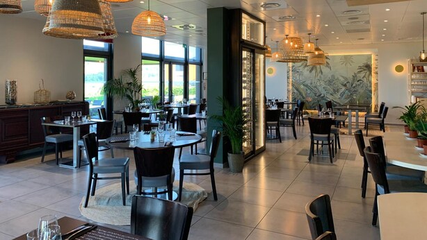 A spacious restaurant with multiple dining areas, large windows, and hanging wicker chandeliers. - Hôtel l'Horizon (Saint-Symphorien-sur-Coise)
