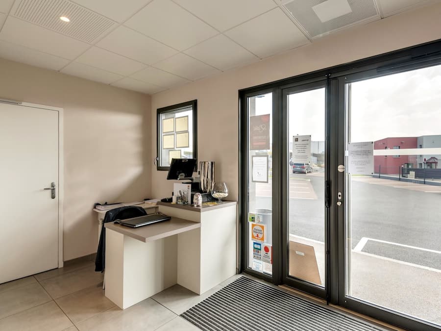 A reception area with a desk, a computer, and a window with a view of the street.