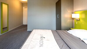 A hotel room with a bed, a green-framed mirror, a door, and a wall-mounted light fixture. - Hôtel l'Horizon (Saint-Symphorien-sur-Coise)