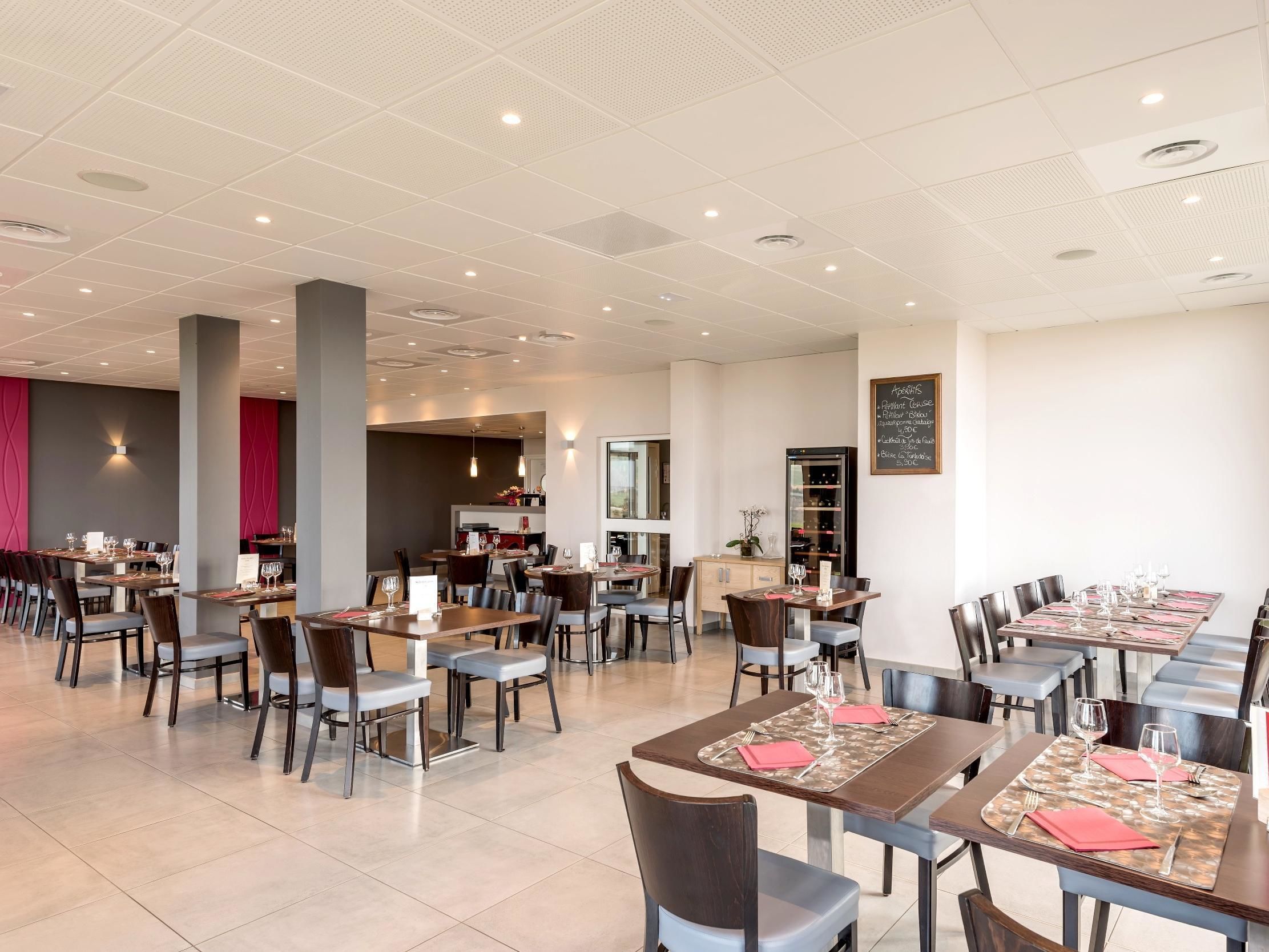 A modern restaurant with multiple dining areas, a visible menu board, and a wine cooler.