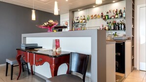 A bar area with a counter, chairs, and a variety of bottles and glasses. - Hôtel l'Horizon (Saint-Symphorien-sur-Coise)