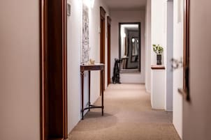 A hallway with a wooden door frame, a small table with a vase, and a mirror on the wall.