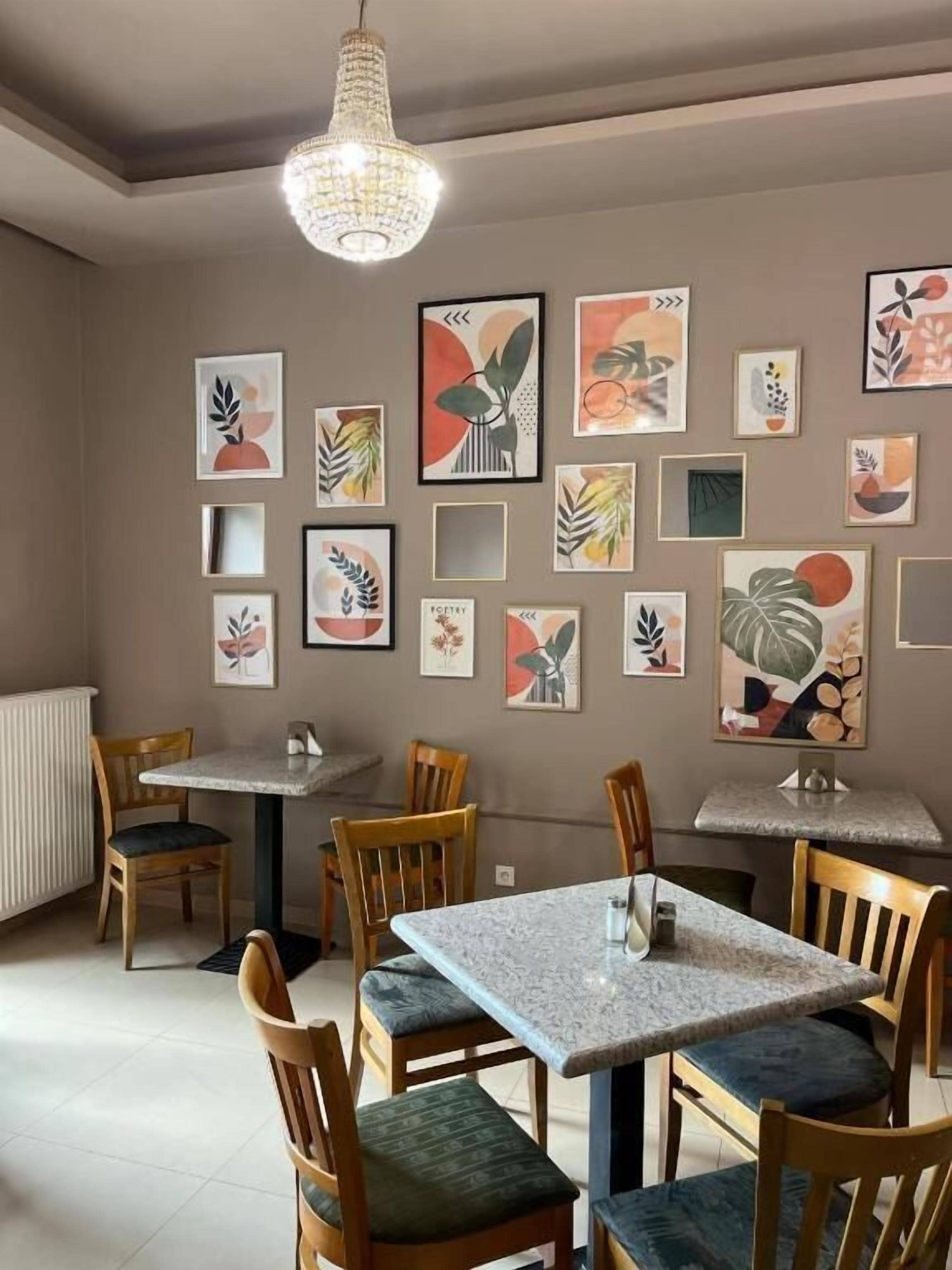 A dining area with wooden chairs and tables, a chandelier, and various framed artworks on the walls.