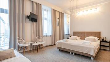 Una habitación de hotel con una cama, dos sillas, un televisor y una mesita de noche.