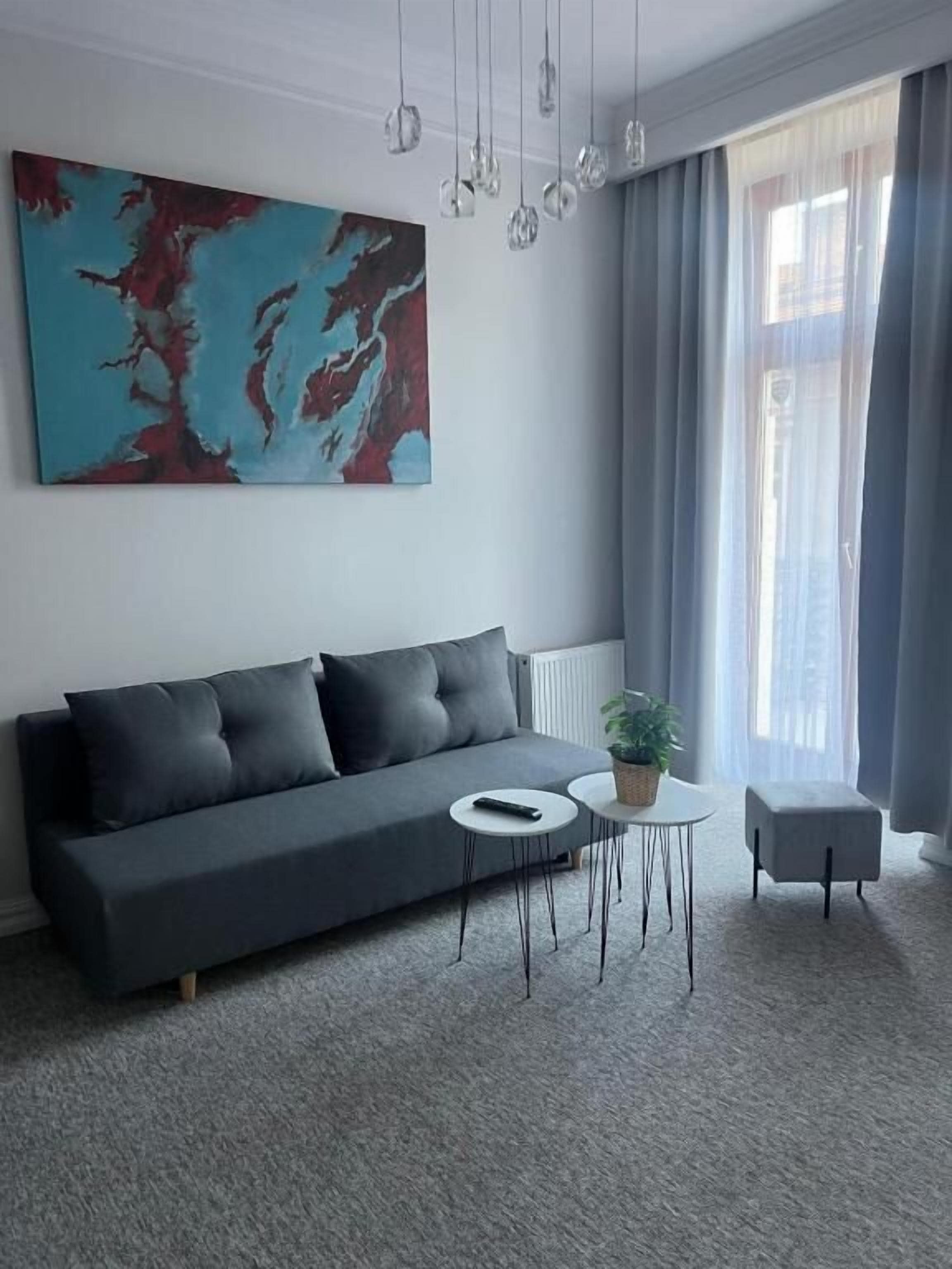 Un salon moderne avec un canapé foncé, une petite table ronde et une plante en pot.