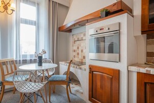 A compact kitchen with a built-in oven, wooden cabinets, and a dining area with chairs and a table.