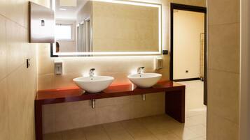 A modern bathroom with two sinks, a large mirror, and a red countertop.