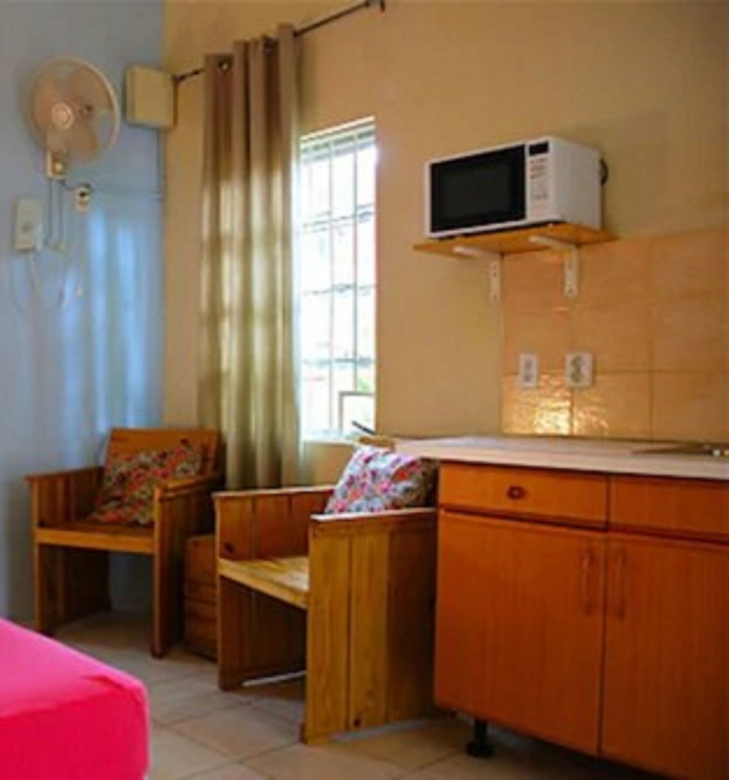 A small room with a wooden desk, a chair, a bed, and a window with curtains.