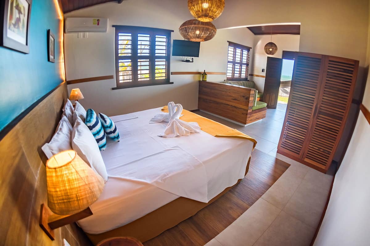 Une chambre à coucher avec un lit, une lampe de chevet, une commode en bois et un téléviseur fixé au mur.