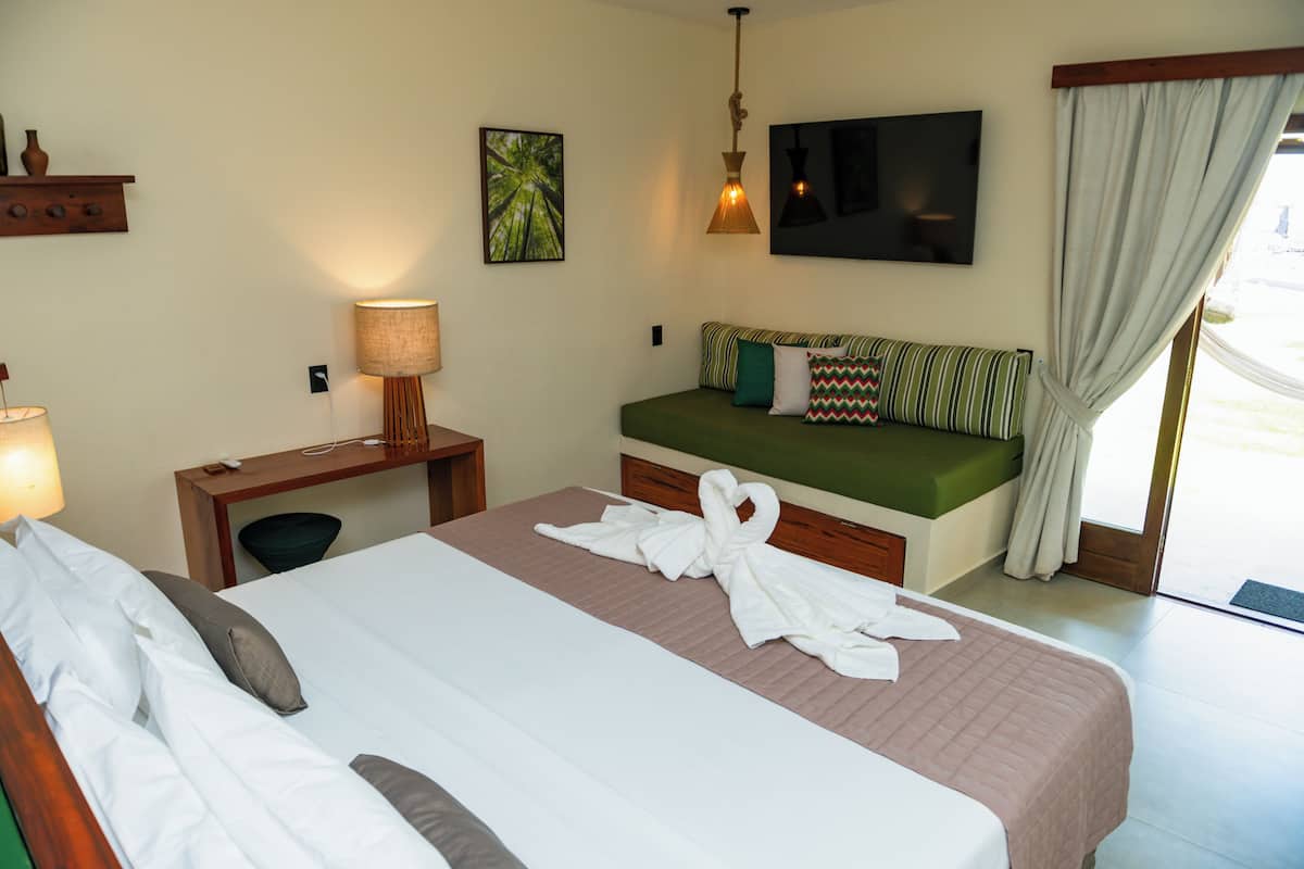 Une chambre d’hôtel équipée d’un lit, d’un bureau, d’une chaise, d’une télévision et d’une fenêtre avec des rideaux.