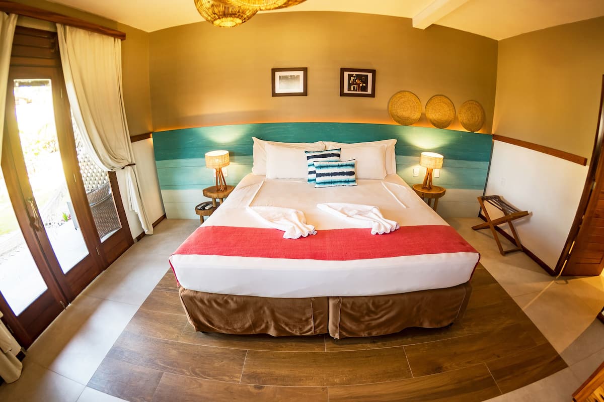 Une chambre d’hôtel avec un grand lit, deux tables de chevet, une porte et une vue sur l’extérieur.