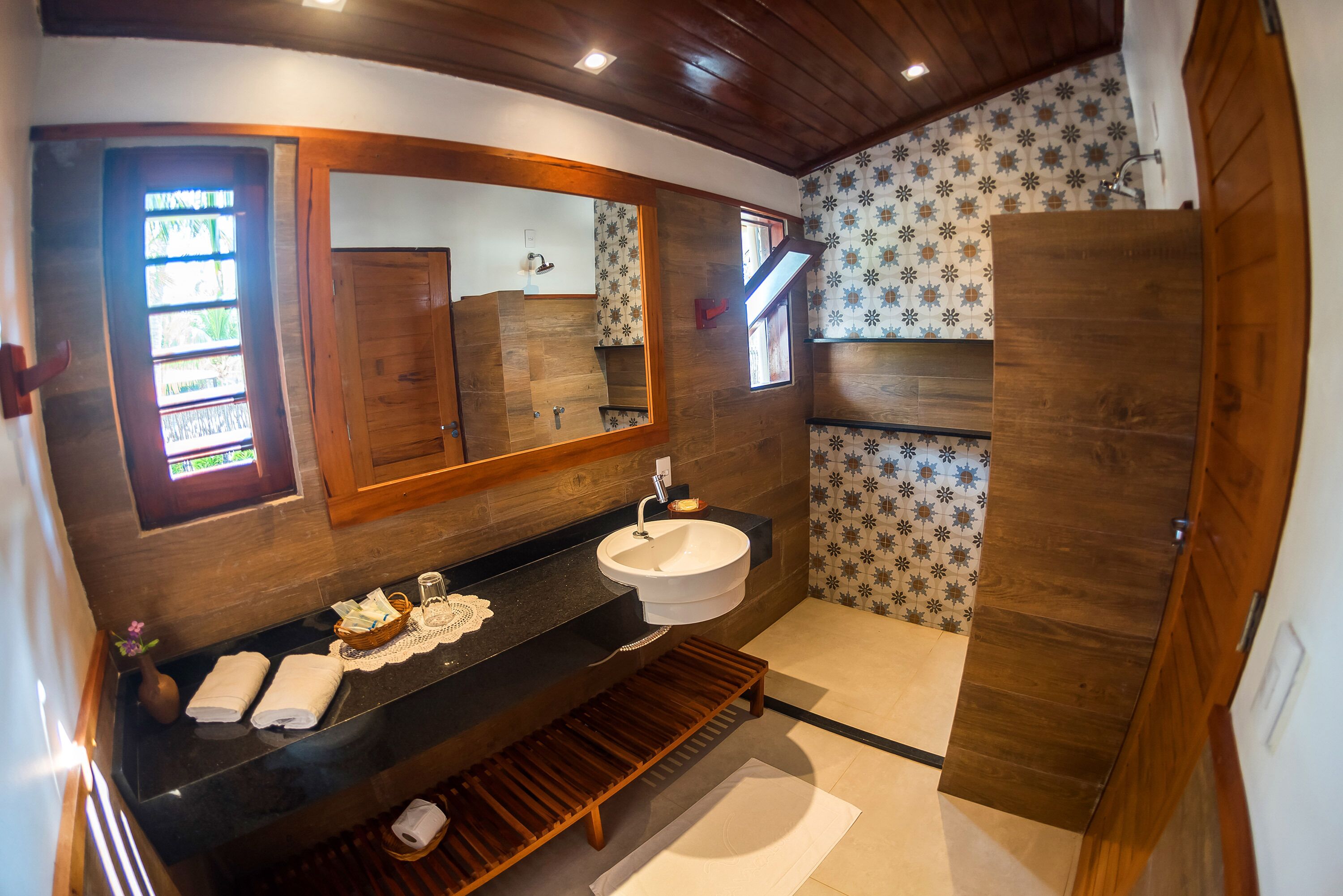 Een moderne badkamer met een houten wastafelmeubel, een grote spiegel en een wastafel.