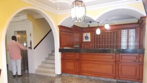 Un interior amplio con suelo de mármol, armarios de madera y una escalera que lleva a un ascensor.