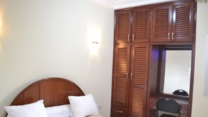 Un dormitorio con cama de madera, un escritorio con silla y un armario.