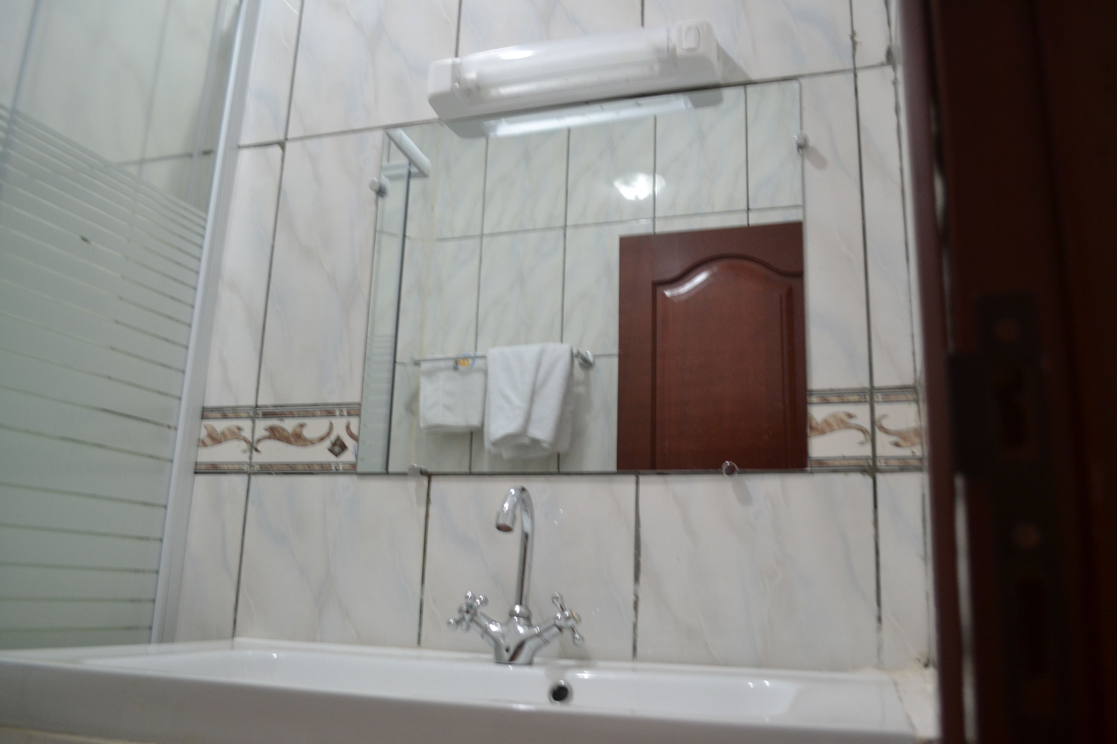 A bathroom with a white sink, a mirror, and a towel hanging on the wall.