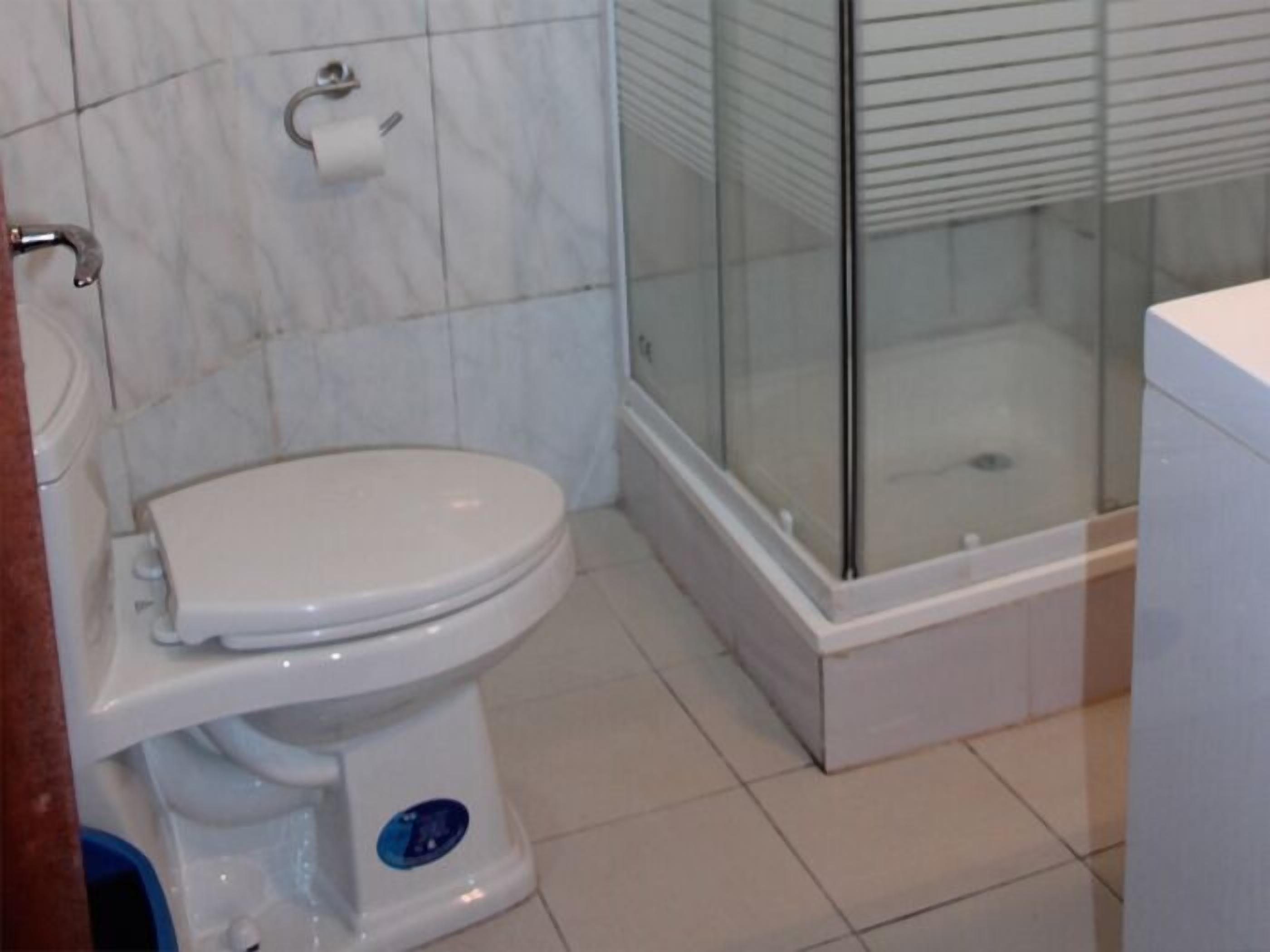 Ein Badezimmer mit Toilette, einer Glasdusche und einem weißen Waschbecken.