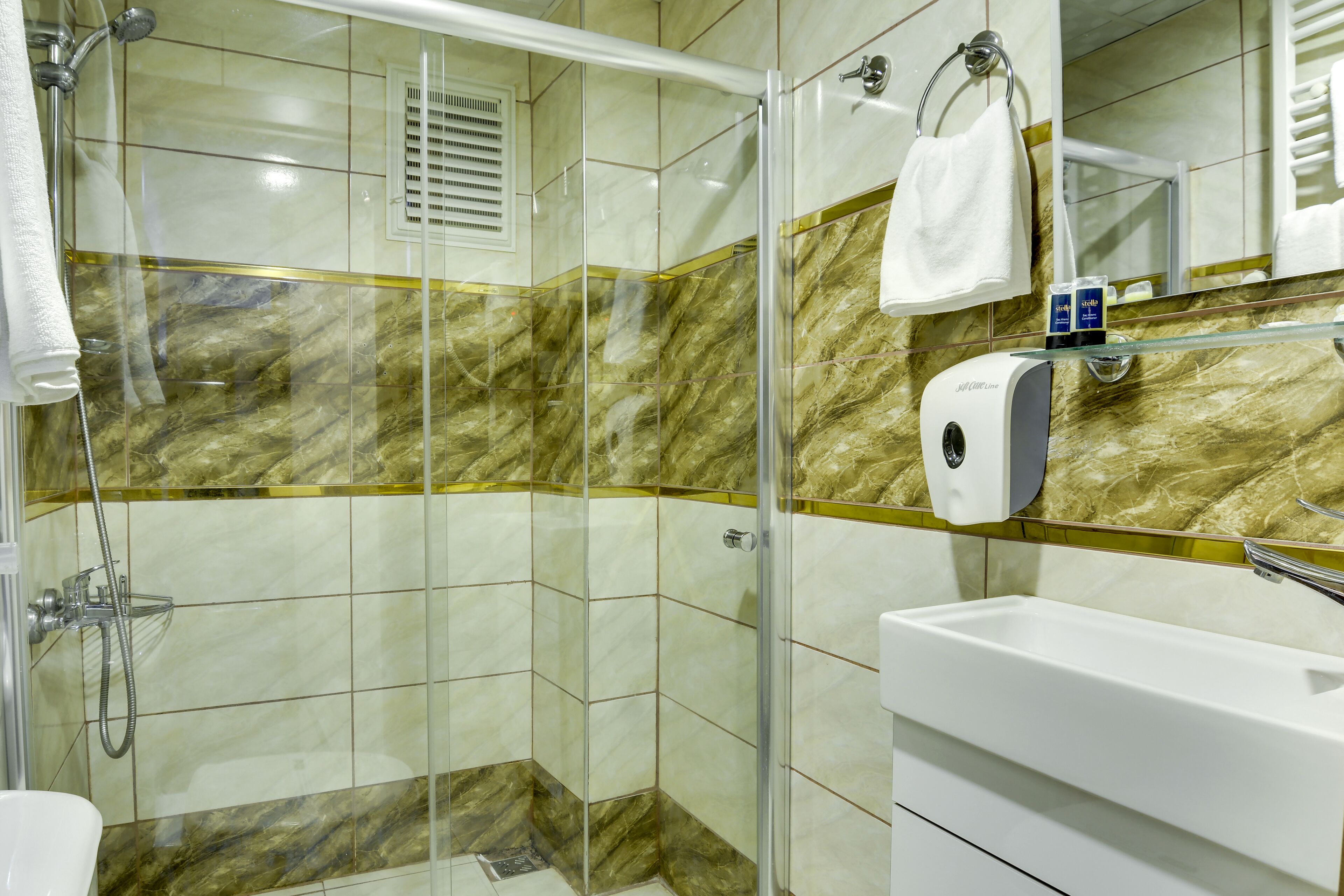 A modern bathroom with a glass-enclosed shower, a white sink, and a marble backsplash.