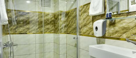 Un baño moderno con ducha de mampara de vidrio, lavamanos blanco y salpicadero de mármol.