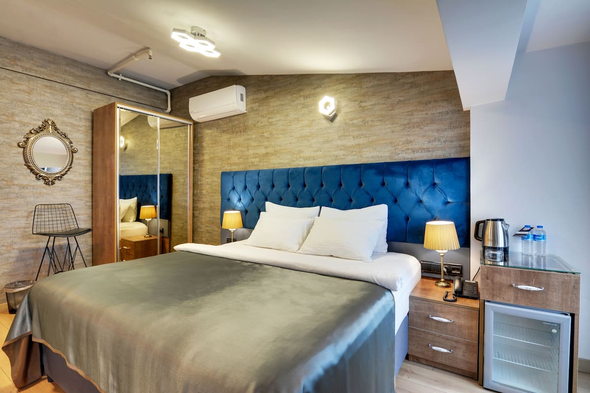 Ein Hotelzimmer mit einem großen Bett, einem Schrank, einem Schreibtisch mit einer Minibar und einem Spiegel an der Wand.