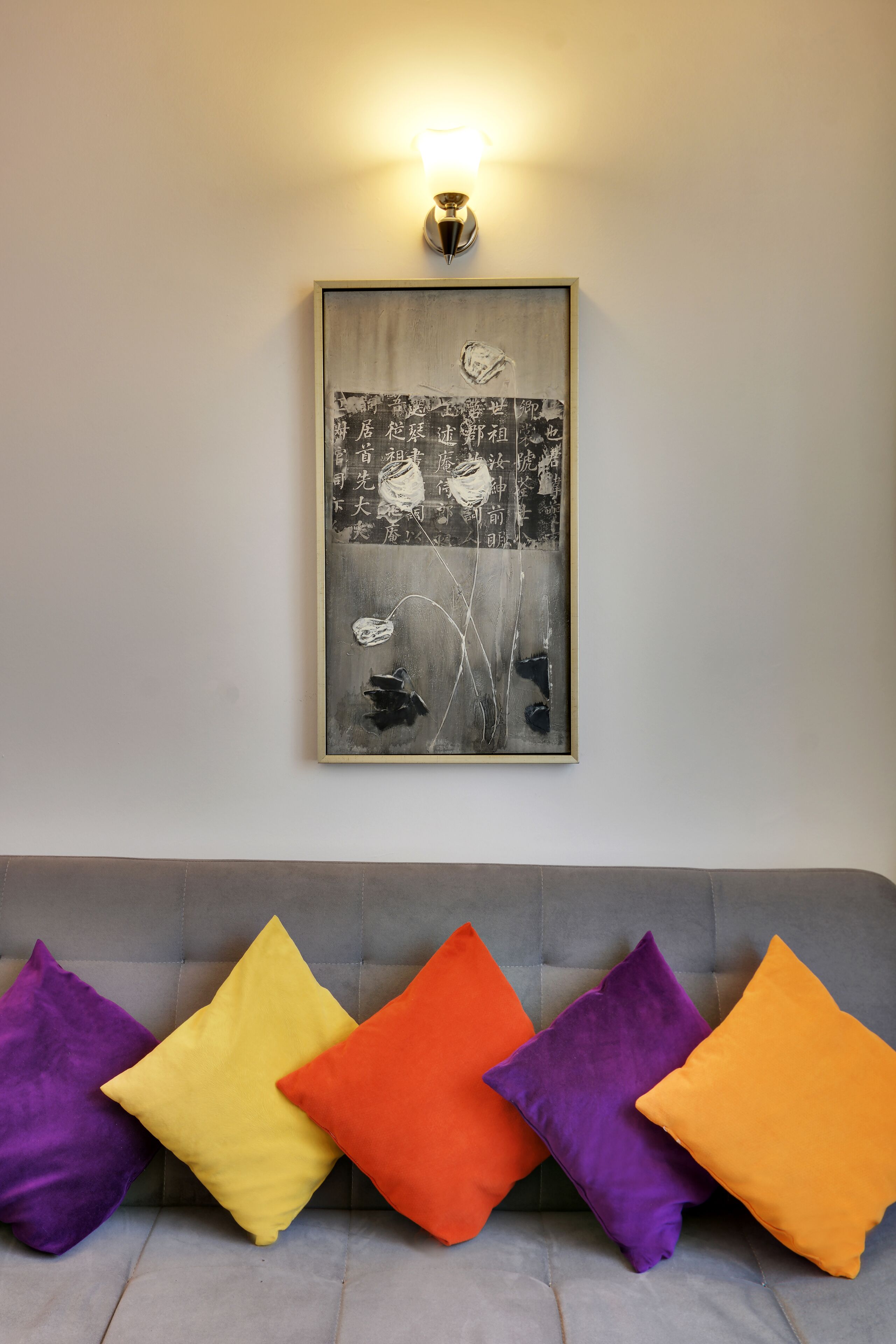 A grey sofa with five colorful cushions in purple, yellow, orange, and red.
