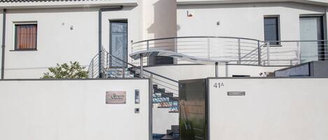 Un edificio moderno con una escalera que conduce a un nivel superior, una barandilla metálica y una puerta con la inscripción '4A'.