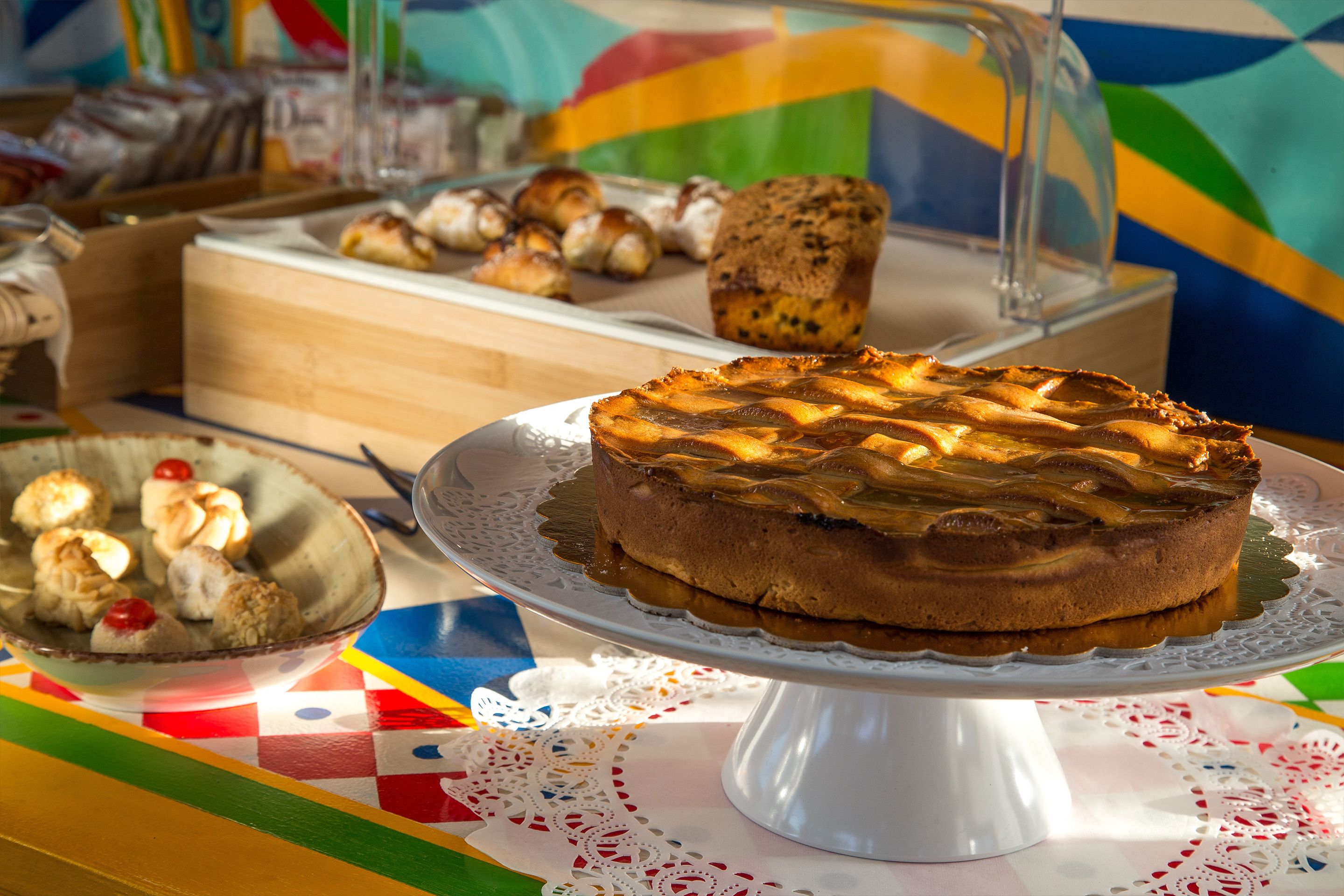 A dessert display with a variety of baked goods including a pie, muffins, and pastries on a colorful tablecloth.