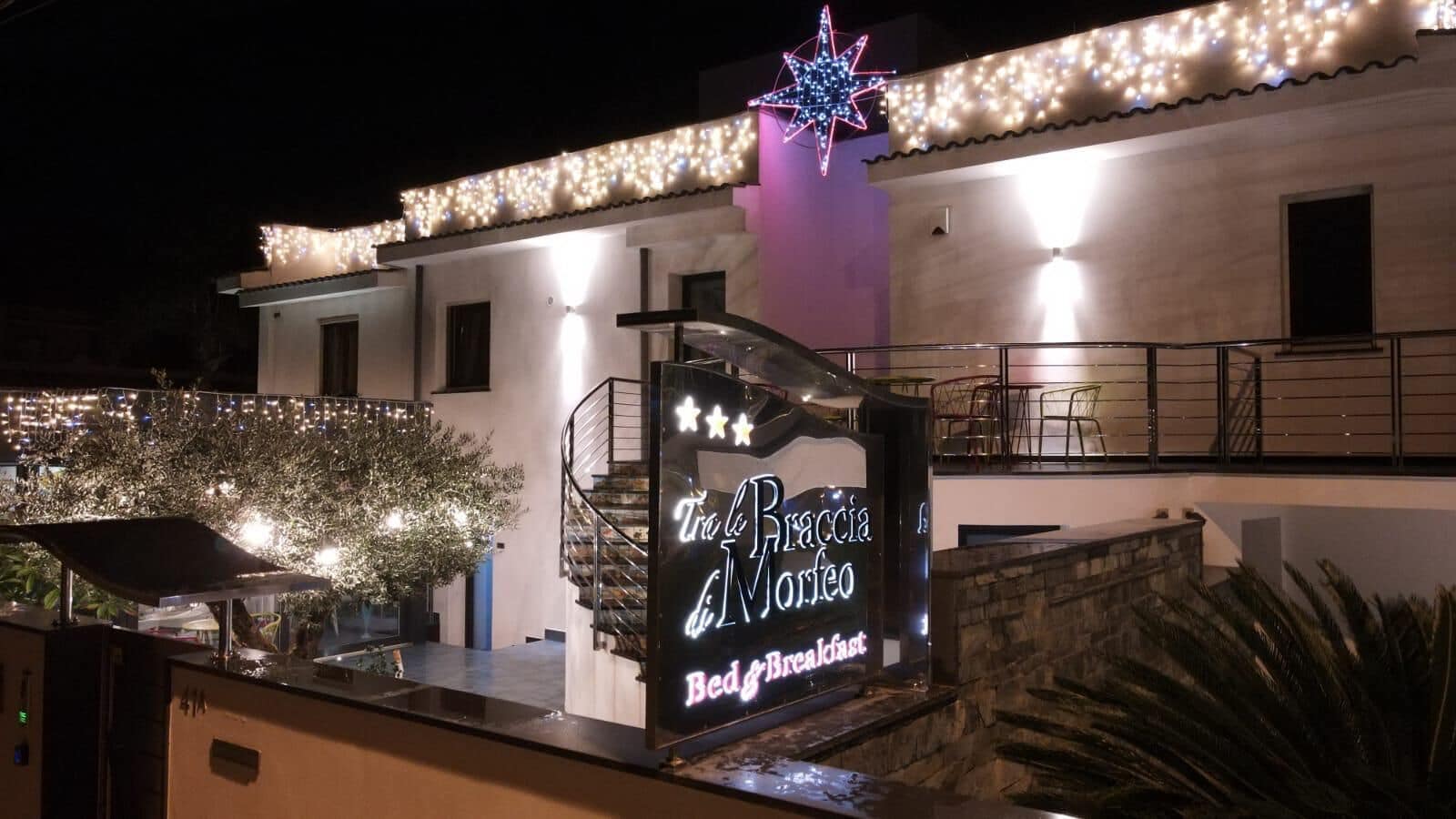 A building with a sign for "Trattoria Braccia di Morfeo Bed & Breakfast" illuminated at night.