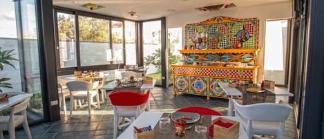 A restaurant with outdoor seating, a colorful cabinet, and a view of the outside.