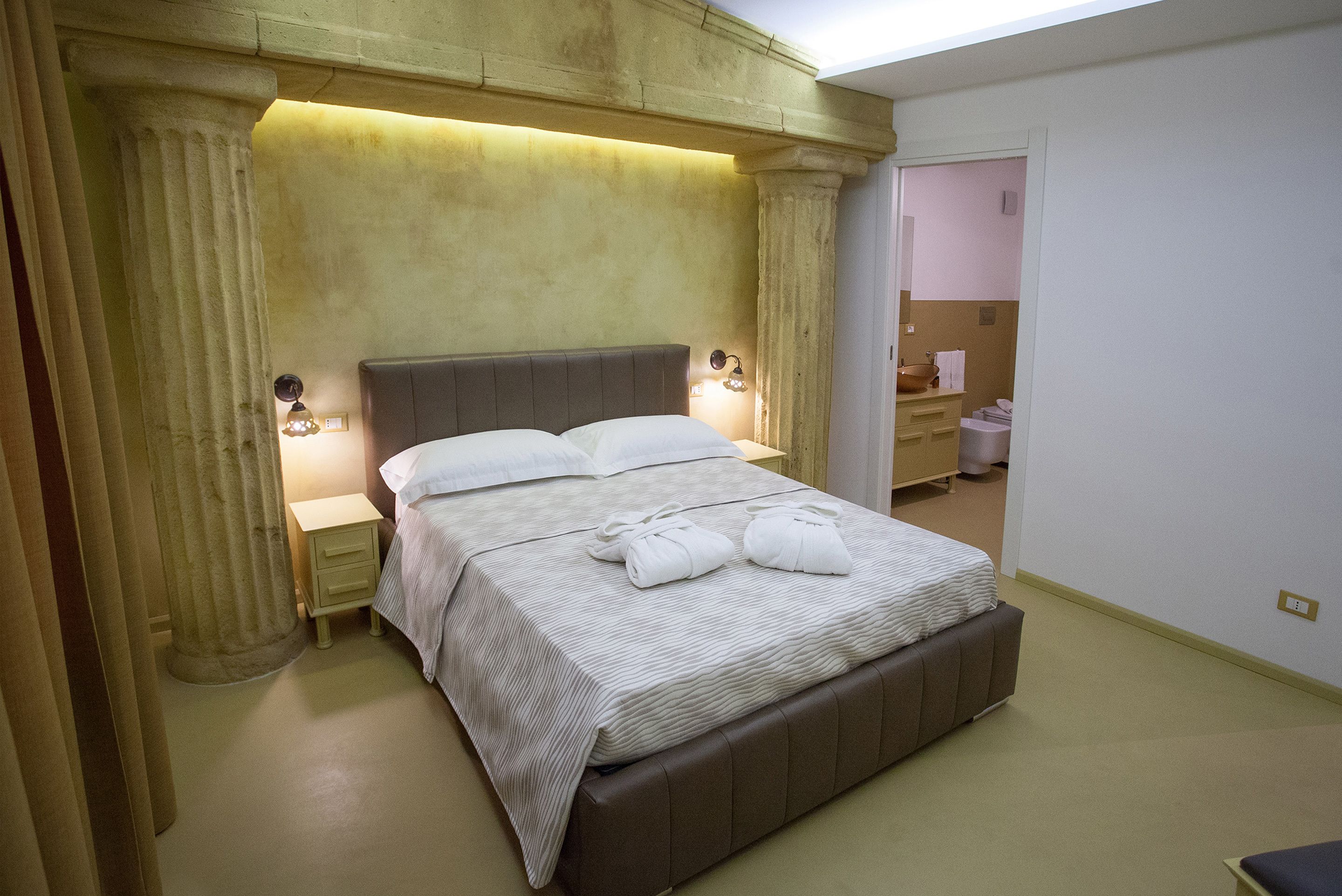 A neatly made bed with a headboard, bedside lamps, and a nightstand.