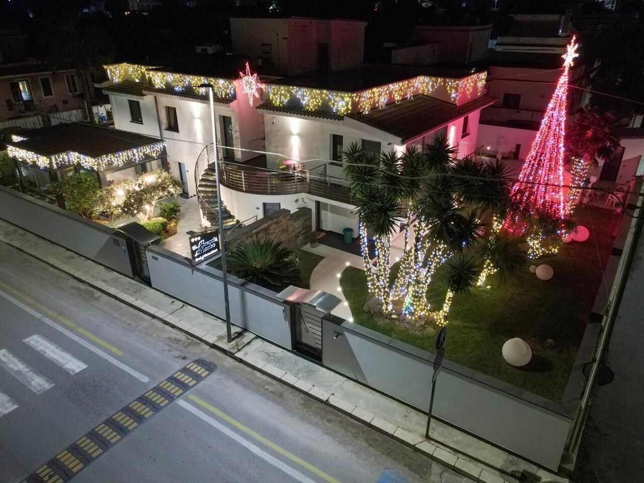 A building with a balcony, a staircase, and a Christmas tree decorated with lights.