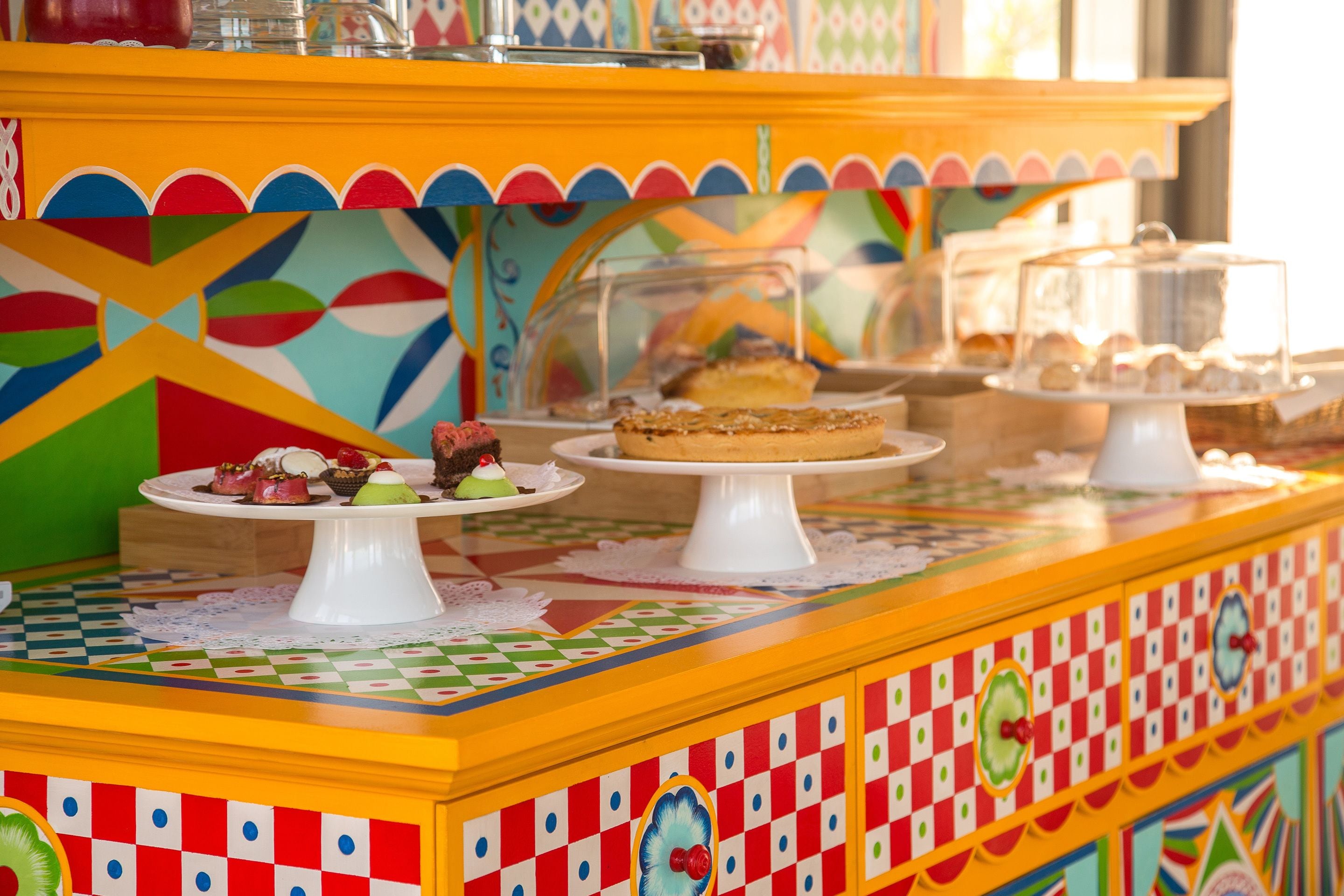 A colorful buffet with various desserts displayed on white stands.