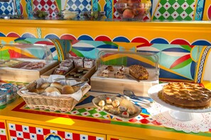 Ein reichhaltiges Buffet mit verschiedenen Speisen und einer Torte auf einem bunten Tisch.