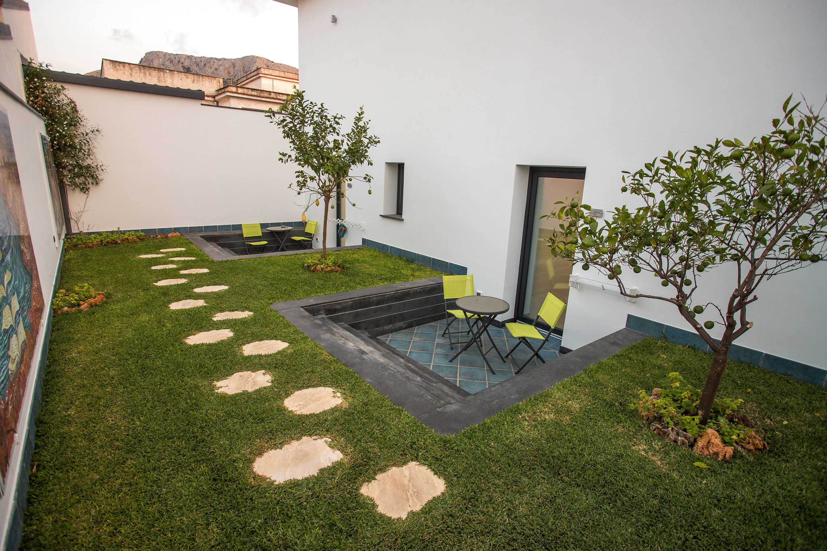 A courtyard with a small seating area, a tree, and a tiled patio.