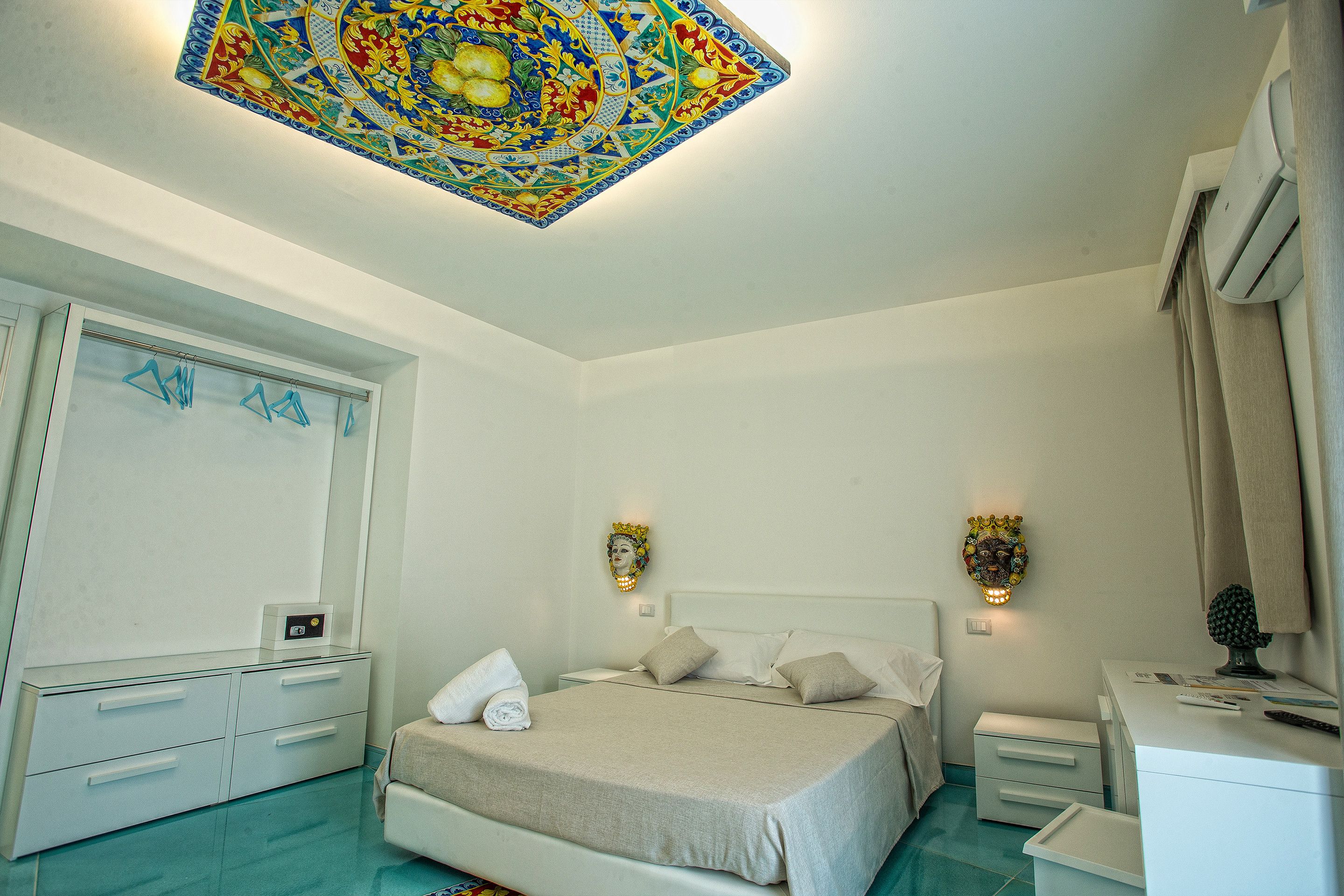 Un dormitorio con cama, mesitas de noche, armario y un techo con diseño decorativo.
