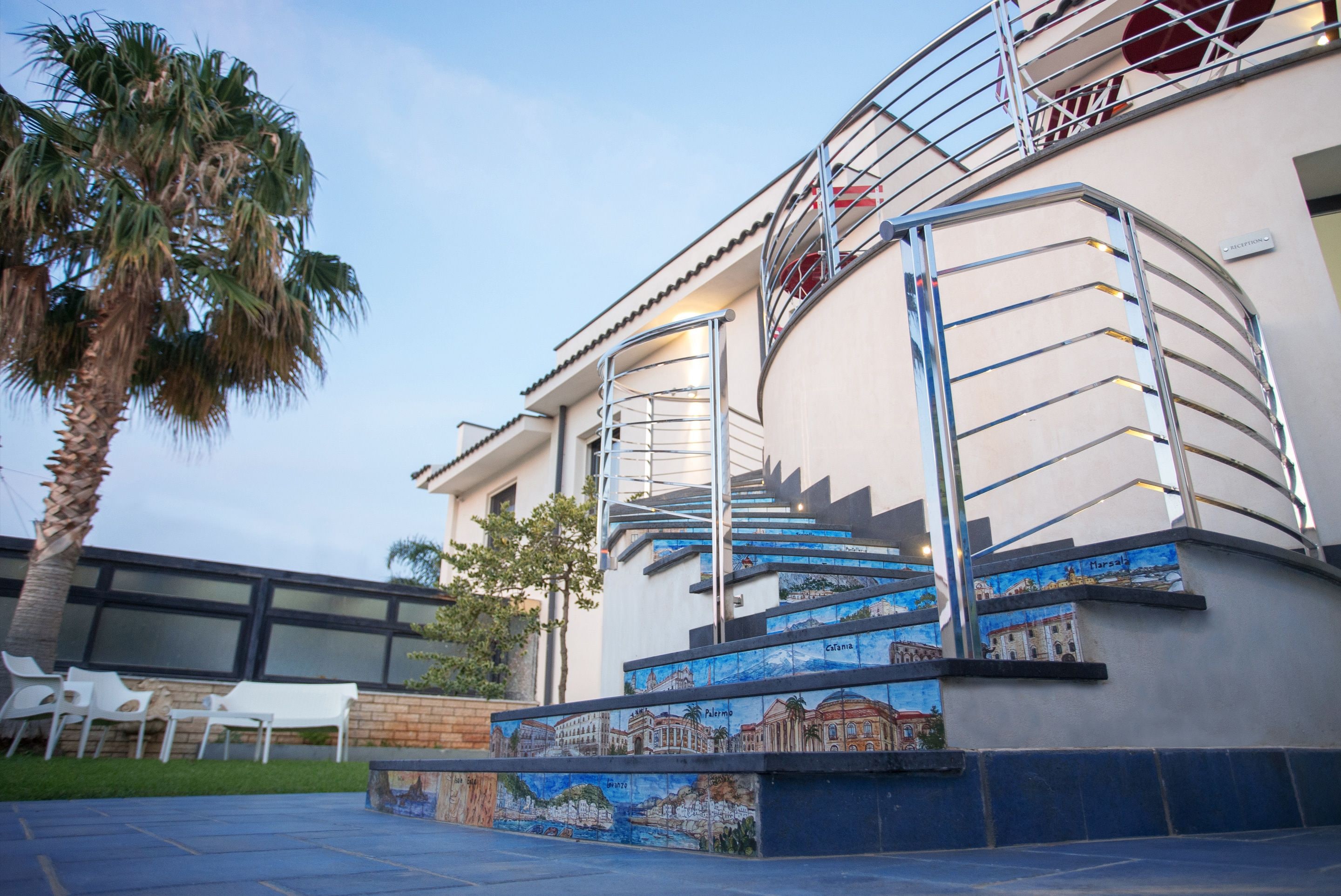 Un edificio con una scala a chiocciola, un murale e una palma.