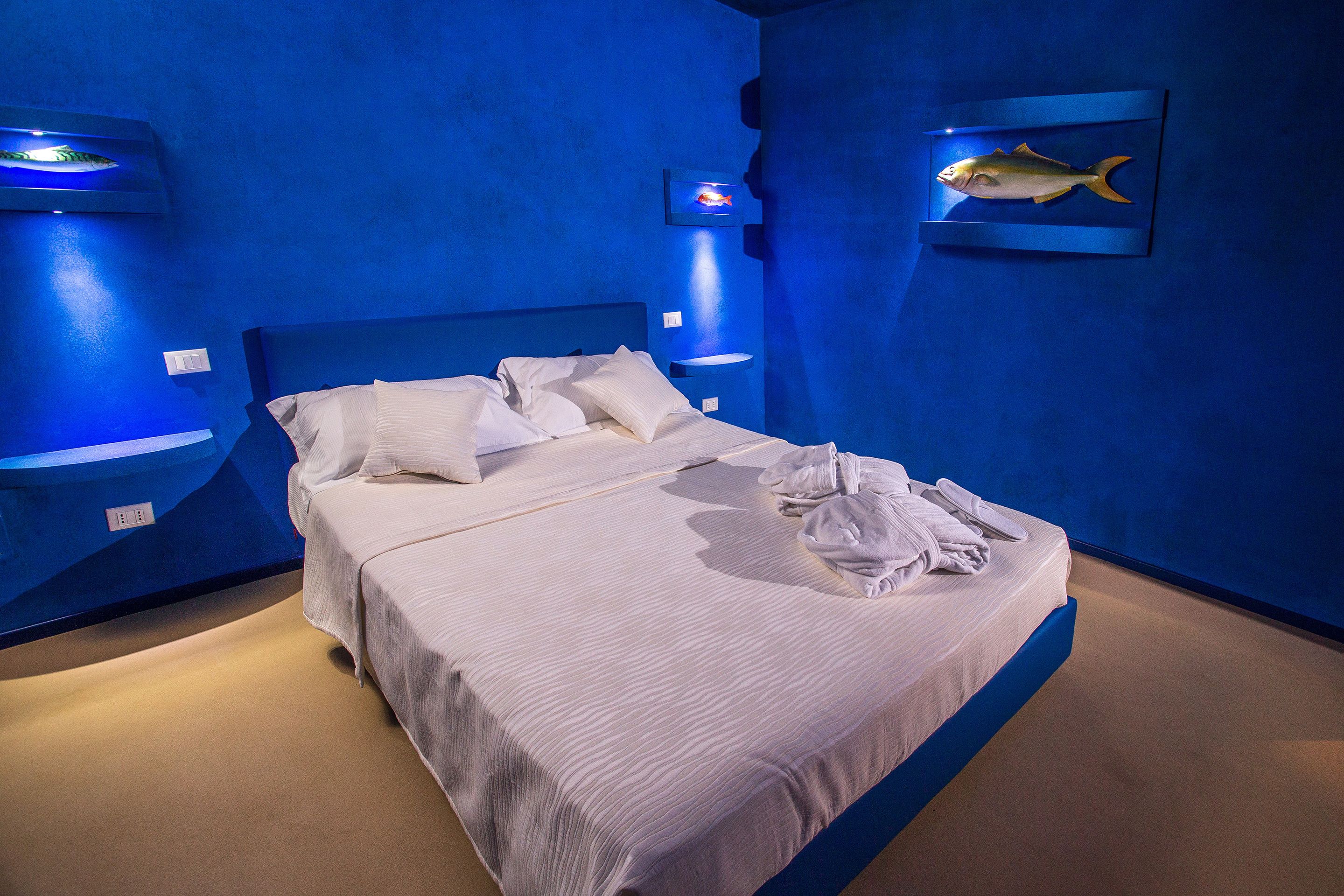 Habitación de hotel con una cama grande, ropa de cama blanca y una pared de acento azul.