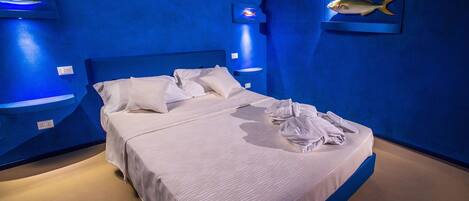 Habitación de hotel con una cama grande, ropa de cama blanca y una pared de acento azul.
