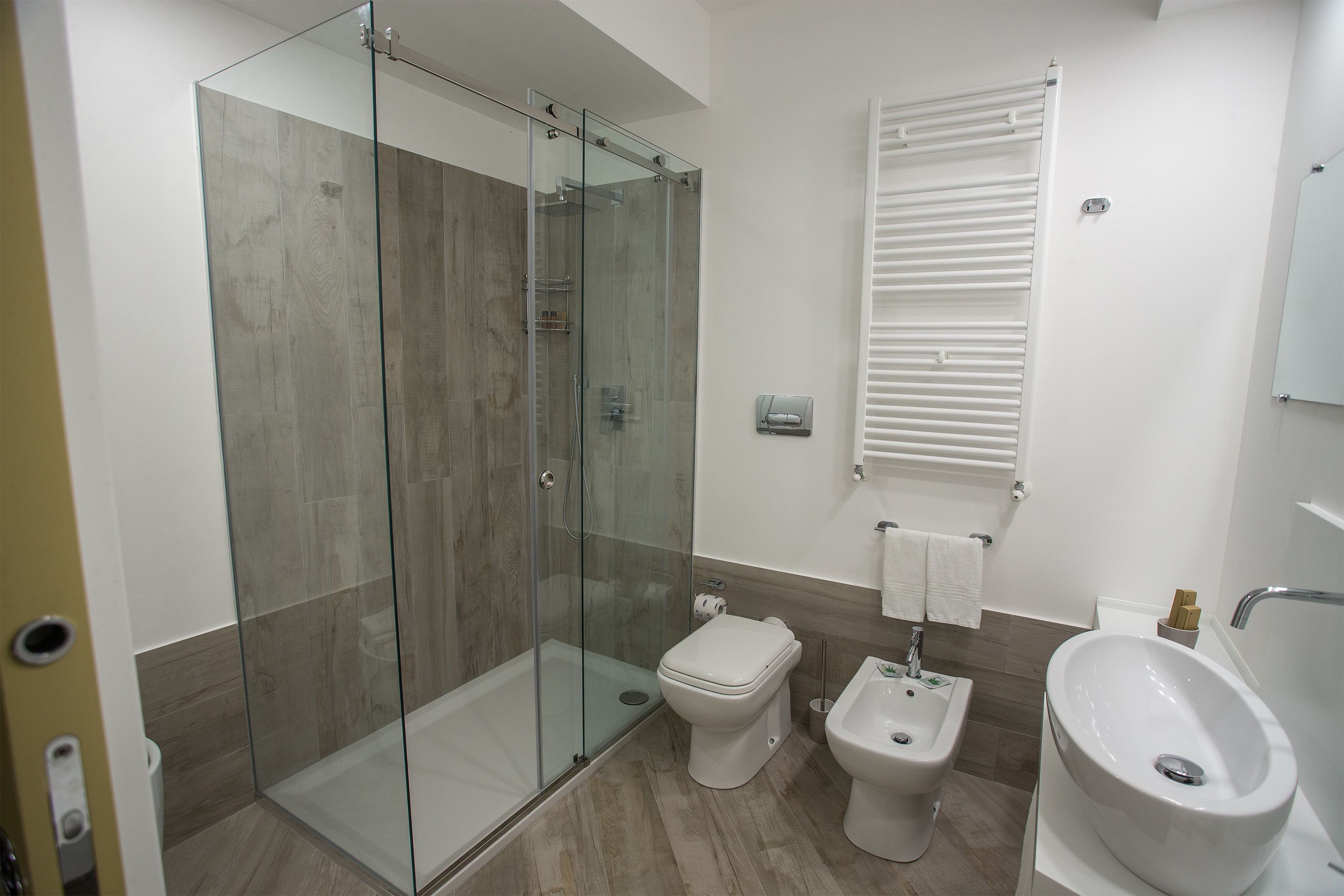 Un baño moderno con ducha de vidrio, inodoro, bidé y lavamanos.