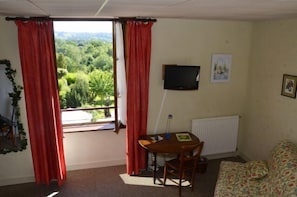 A room with a table, a TV, and a sofa. - Auberge la Source (Cieux)