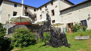 A stone building with outdoor umbrellas, a staircase, and a garden. - Auberge la Source (Cieux)
