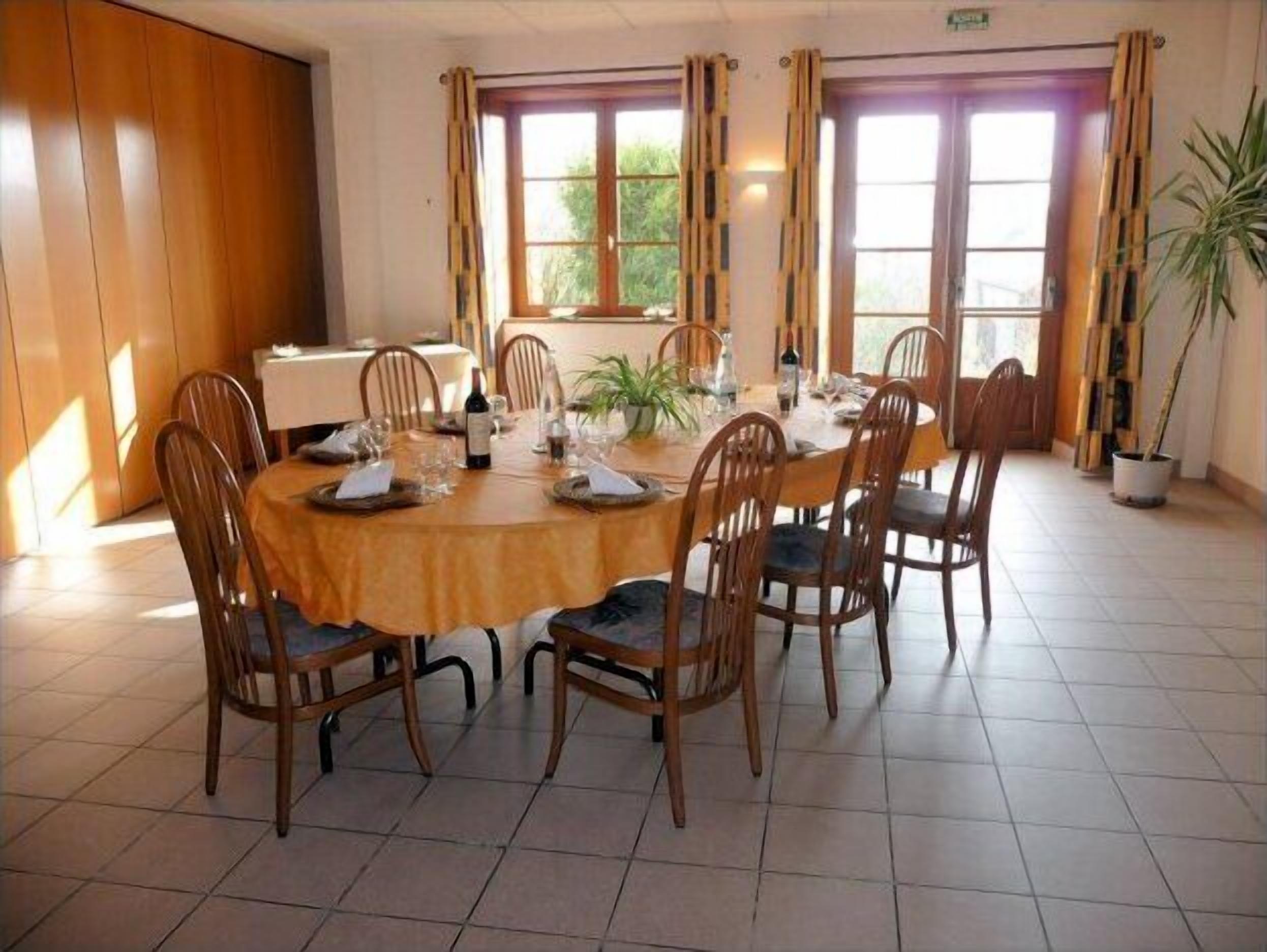Un comedor con una mesa redonda preparada para seis personas, rodeada de sillas de madera.