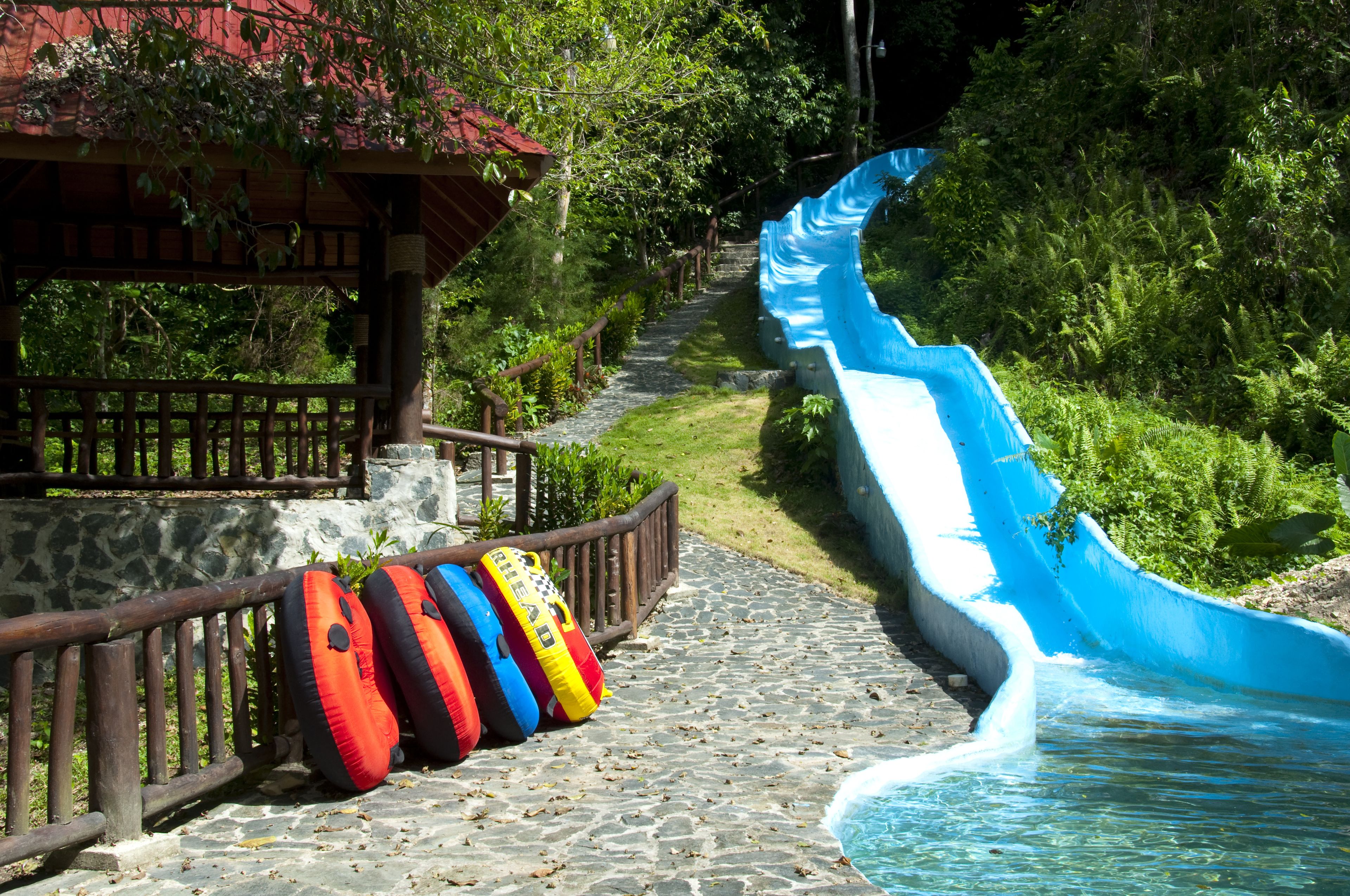 A water slide with a wooden pathway leading to a covered area with inflatable rings.