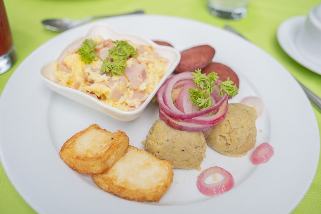 A plate with scrambled eggs, fried potatoes, and sliced red onions garnished with parsley.
