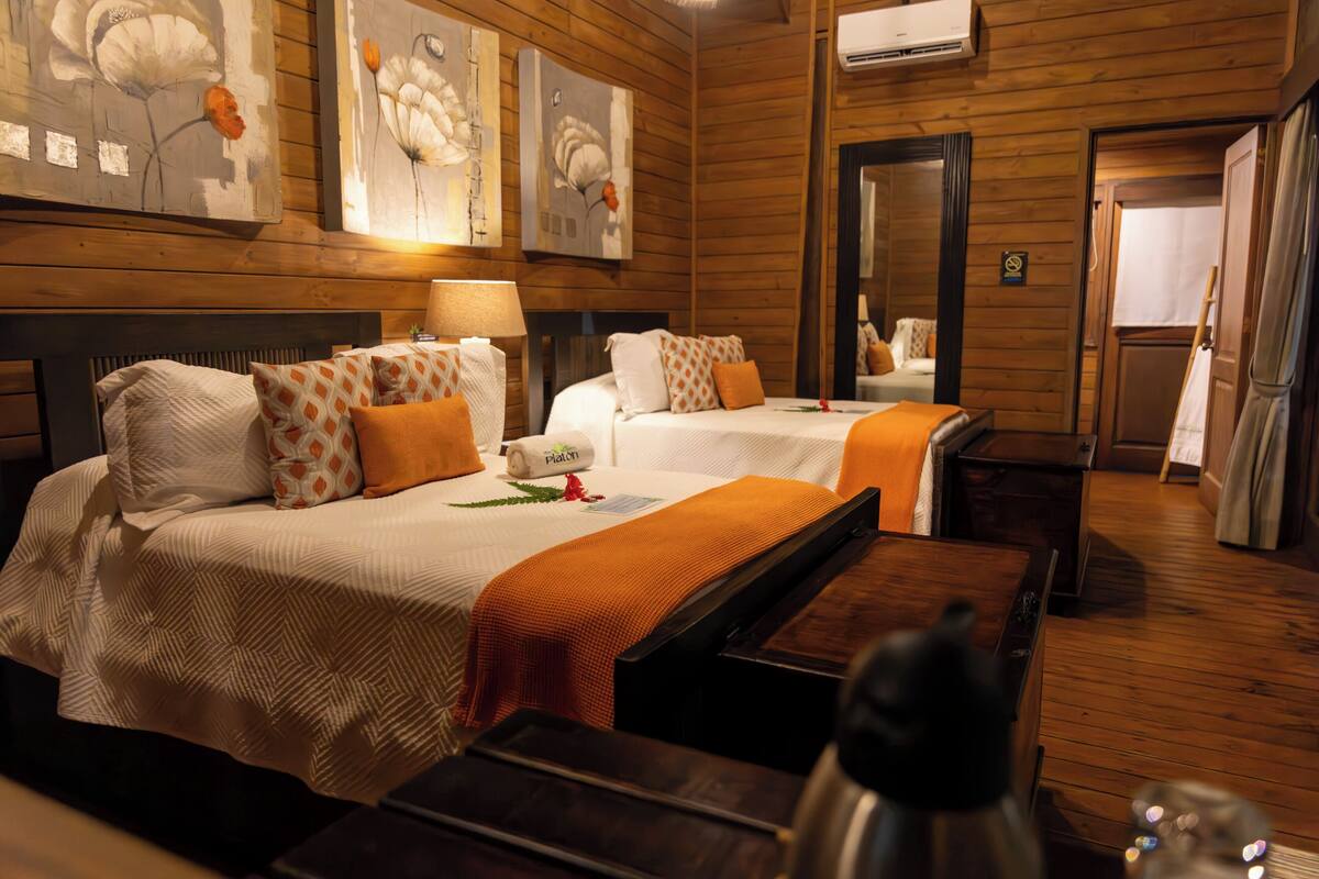 Habitación de hotel con dos camas, paredes de madera y obras de arte decorando las paredes.